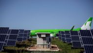 A passenger commercial aircraft on the runway at George Airport before take off, as solar panels are seen in the foreground. AFP / GIANLUIGI GUERCIA 
