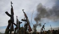 Rebel fighters hold up their rifles as they walk in front of a bushfire in a rebel-controlled territory in Upper Nile State, South Sudan February 13, 2014. REUTERS/Goran Tomasevic