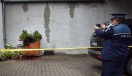 A policeman takes pictures of a bear lying in a flower box after he was shot dead in downtown Sibiu, Romania, on October 12, 2016. The brown bear has walked several hours in the morning through central Sibiu before being shot, local authorities said. / AF