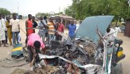 People gather at the site of a car blast in Maiduguri, northeast Borno State in Nigeria, on October 12, 2016 where 8 people were killed and dozen injured. / AFP / STRINGER.