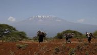 Mount Kilimanjaro is seen behind maasai women carrying firewood outside Amboseli National Park, southeast of Kenya's capital Nairobi, March 26, 2016. REUTERS/Thomas Mukoya