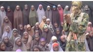 This video grab image created on August 14, 2016 taken from a video released on youtube purportedly by Islamist group Boko Haram showing what is claimed to be one of the groups fighters at an undisclosed location standing in front of girls allegedly kidna