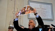 An opposition city councillor holds a placard picturing Rome's mayor Virginia Raggi and her head of personnel Raffaele Marra, as he protests during the town council assembly at the Campidoglio, in Rome, on December 16, 2016. Rome's mayor Virginia Raggi, t