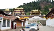 A monk pauses to look at a taxi arriving for pickup at Sertri Monastery, one of two in Langmusi, a small town that straddles China's Sichuan and Gansu provinces. (Photos by William Ford for The Washington Post)