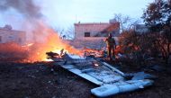 A picture taken on February 3, 2018, shows a Rebel fighter taking a picture of a downed Sukhoi-25 fighter jet in Syria's northwest province of Idlib.   AFP / OMAR HAJ KADOUR