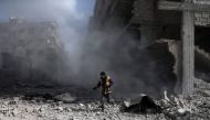 A civil Defence volunteer, known as the White Helmets, checks the site of a regime air strike in the rebel-held town of Saqba, in the besieged Eastern Ghouta region on the outskirts of the capital Damascus, on February 23, 2018.  AFP / ABDULMONAM EASSA
