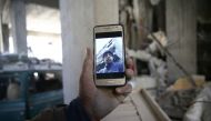 Abu Mohammad Alaya, 50, holds a mobile phone with his son Mohammad's picture on the screen, who was killed, in Douma, Syria March 2, 2018. Picture taken March 2, 2018. Reuters/Bassam Khabieh