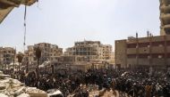 A picture taken on March 25, 2018 shows Syrian civilians gathering for their evacuation from the town of Arbin in the Eastern Ghouta region on the outskirts of the capital Damascus, following a deal with the regime. AFP / AMER ALMOHIBANY
