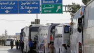 A convoy transporting Syrian civilians and rebel fighters evacuated from Eastern Ghouta arrives in a government-held area at the entrance of Harasta on the outskirts of the capital Damascus, on March 26, 2018.  AFP / LOUAI BESHARA
