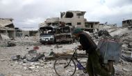 A man walks with his bicycle at a damaged site in the besieged town of Douma, Eastern Ghouta, in Damascus, Syria March 30, 2018. REUTERS/Bassam Khabieh
