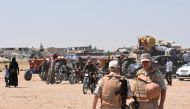 FILE PHOTO: Russian and Syrian forces stand guard as civilians enter the Abu Duhur crossing on the eastern edge of Idlib province on August 20, 2018. AFP / George OURFALIAN
