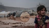 Syrians are seen on the mud-covered road between tents at a refugee camp, where Syrian refugees live, after heavy rain at winter season in northeastern Idlib, Syria on December 13, 2019. Muhammed Said - Anadolu 