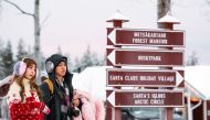 Tourists look at information boards during their visit to the Santa Claus Village near Rovaniemi, Finnish Lapland, on December 2, 2019. AFP / Jonathan Nackstrand