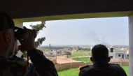 Syrian army soldiers watch over the Turkish and Russian military joint patrol on the M4 highway, which links the northern Syrian provinces of Aleppo and Latakia, on March 15, 2020.   AFP 