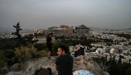 (FILES) In this file photo taken on May 17, 2020 people sit on a hill facing the ancient Temple of Parthenon atop the Acropolis hill in Athens on May 17, 2020 during the gradual deconfinement started on May 4, following a lockdown aimed at curbing the spr