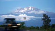 A vehicle drives past Mount Kilimanjaro in Tanzania's Hie district December 10, 2009. At the foot of Africa's snow-capped Mount Kilimanjaro, images of the mountain adorn the sides of rusting zinc shacks and beer bottle labels, but the fate of the real ver