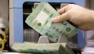 FILE PHOTO: A man counts Lebanese pound banknotes at a currency exchange shop in Beirut, Lebanon, January 5, 2022. Picture taken January 5, 2022. REUTERS/Mohamed Azakir