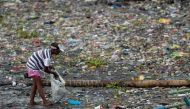 A woman picks up plastic cups along the riverbank of Pasig river, in Manila, Philippines, June 10, 2021. REUTERS/Lisa Marie David/File Photo