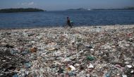 A man walks by garbage at a polluted beach on the banks of Guanabara Bay in Rio de Janeiro, Brazil March 16, 2022. REUTERS/Ricardo Moraes
