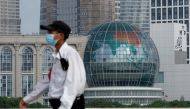 A security guard wearing a face mask following the coronavirus disease (Covid-19) outbreak walks past a globe in Shanghai, China, August 2, 2022. (REUTERS/Aly Song)