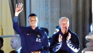 France's forward Kylian Mbappe (left) and coach Didier Deschamps greet supporters at the Hotel de Crillon, on Monday. 