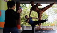 In this photo taken on July 15, 2023 visitors take pictures with a statue of Bruce Lee outside the Hong Kong Heritage Museum in Hong Kong, ahead of the 50th anniversary of the martial arts star's death on July 20. Photo by May JAMES / AFP