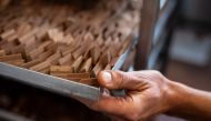 A worker moves a tray of the famous chocolate treat shaped like lingots, the 'Gianduiotto' made with cacao, sugar and hazelnut, on December 12, 2023 in Giaveno near Turin, Northwestern Italy. Photo by MARCO BERTORELLO / AFP