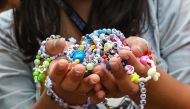 (Files) A fan of US singer Taylor Swift, also known as a Swiftie, holds friendship bracelets as she arrives for the first of the pop star's six sold-out Eras Tour concerts at the National Stadium in Singapore on March 2, 2024. (Photo by Roslan Rahman / AFP)