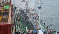 A bunkering barge (R) supplies fuel to a container ship (L) with 