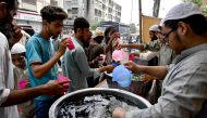 Volunteers distribute chilled soft drinks to people at a heatwave relief camp along a roadside on a hot summer afternoon in Karachi on June 3, 2024. (Photo by Asif HASSAN / AFP)