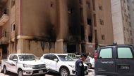 A member of the Kuwaiti security forces stand outside a building which was ingulfed by fire, in Kuwait City, on June 12, 2024. (Photo by Yasser Al-Zayyat / AFP)
