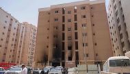 People walk past a building which was ingulfed by fire, in Kuwait City, on June 12, 2024. Photo by Yasser Al-Zayyat / AFP.