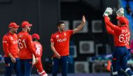 Mark Wood (center) of England celebrates the dismissal of Kashyap Prajapati of Oman during the ICC Men's T20 CWC group B match between England and Oman at Vivian Richards Cricket Stadium in North Sound, Antigua and Barbuda, on June 13, 2024. (Photo by Randy Brooks / AFP)
