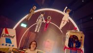 A gallery assistant looks at a Barbie doll taken to space by European Space Agency (ESA) astronaut and Europe's first female commander of the International Space Station Samantha Cristoforetti (top R) at The Design Museum in London on July 1, 2024. (Photo by Benjamin Cremel / AFP)