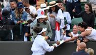 Japan's Naomi Osaka stands on a bench to sign autographs after winning against France's Diane Parry during their Women's singles tennis match on the first day of the 2024 Wimbledon Championships at The All England Lawn Tennis and Croquet Club in Wimbledon, southwest London, on July 1, 2024. (Photo by ANDREJ ISAKOVIC / AFP)
