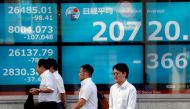 File photo: Men walk past in front of an electric screen showing Japan's Nikkei share average outside a brokerage in Tokyo, Japan, August 5, 2019. File Photo: REUTERS/Issei Kato

