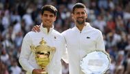 Spain's Carlos Alcaraz holding the winner's trophy (left) and second-placed Serbia's Novak Djokovic pose for pictures during the price ceremony at the end of their men's singles final tennis match on the fourteenth day of the 2024 Wimbledon Championships at The All England Lawn Tennis and Croquet Club in Wimbledon, southwest London, on July 14, 2024. (Photo by Andrej Isakovic / AFP) 