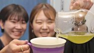 A participant at Edo Saryo (Craft and Cafe) Aoyama pours tea into a cup that has just been painted before enjoying it with a friend. (Photo by Yoshinobu Goto/The Japan News)

