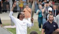 US rapper Snoop Dogg makes a peace sign as he holds the torch as part of the 2024 Paris Olympic Games Torch Relay, on the day of the opening ceremony, in Saint-Denis, outside Paris, on July 26, 2024. (Photo by STEPHANE DE SAKUTIN / AFP)