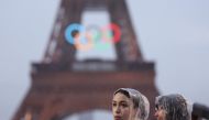 Spectators wear ponchos to shelter from the rain beside the Eiffel Tower during the opening ceremony of the Olympic Games Paris 2024 on July 26, 2024 in Paris, France. Photo by Cameron Spencer / POOL / AFP