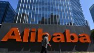 A woman walks past an Alibaba sign outside the company's office in Beijing on April 13, 2021. Photo by GREG BAKER / AFP