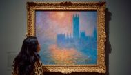 A gallery assistant studies a work by the french impressionist painter Claude Monet, 