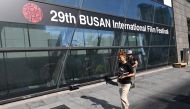 Pedestrians walk past past a banner for the 29th Busan International Film Festival (BIFF) at the Busan Cinema Center in Busan on October 2, 2024. (Photo by Jung Yeon-je / AFP)