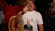 A supporter of Tunisia's President celebrates after the announcement of the first estimates in favor of the incumbent President, on the Avenue Habib Bourguiba in Tunis on October 6, 2024. (Photo by YASSINE MAHJOUB / AFP)
