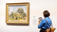 A woman looks at the work 'Landscape near Aix with Tour de Cesar' by Paul Cezanne from the new exhibition 'Vive l'impressionnisme!' at the Van Gogh Museum in Amsterdam on October 9, 2024. (Photo by Robin van Lonkhuijsen / ANP / AFP)