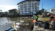 Contractors work to remove garbage and debris from Clearwater Bay in Clearwater Beach, Florida, following the passage of Hurricane Milton on October 11, 2024. 