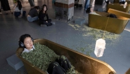 Visitors submerge themselves in tubs filled with dried leaves, as part of an interactive artwork by Serbian conceptual artist Marina Abramovic on October 11, 2024. (Photo by AFP) 