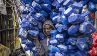 Ezedin Muste moves a huge pile of plastic soap containers at the historical Merkato district of Addis Ababa on October 1, 2024. (Photo by Michele Spatari / AFP)