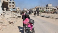 A woman pushing a wheel chair loaded with her personal belongings as displaced Palestinians fleeing Israeli military operations in Beit Lahia in the northern Gaza strip walk along the Salah al-Din main road in eastern Gaza City making their way to the city centre, on October 22, 2024. (Photo by Omar Al-Qattaa / AFP)