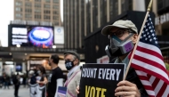 File photo for representational purposes only: A man wearing a protective mask due to COVID-19 pandemic holds a sign outside Madison Square Garden, which is used as a polling station, on the first day of early voting in Manhattan, New York, U.S. October 24, 2020. REUTERS/Jeenah Moon/File P